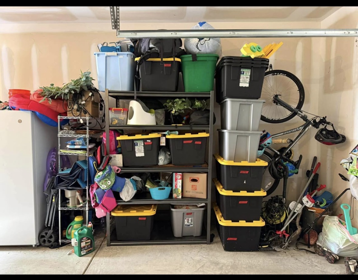 Cluttered garage before a Tote Wall installation with mixed bins, tools, bicycles, and loose household items