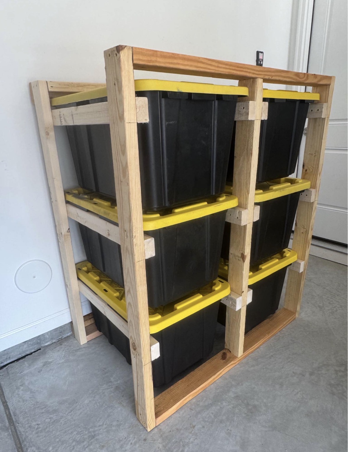 Side view of a compact six-tote wood storage wall showing individual tote supports